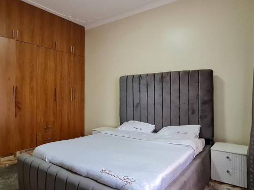 um quarto com uma cama grande e uma cabeceira cinzenta em Jay's Villa em Kampala