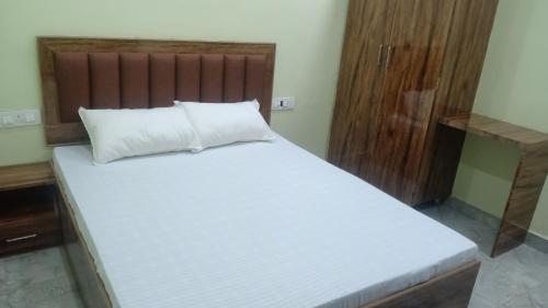 a bedroom with a large white bed with a wooden headboard at Shagun Banquet and Hotel in Gwalior