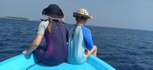 dos chicas sentadas en una tabla de paddle en el agua en Himandhoo Travel & Stays en Alifu Atoll