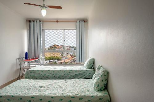 1 dormitorio con 2 camas y ventana en APARTAMENTO, ATÉ 4 PESSOAS,20 Metros da PRAIA do SONHO, PÉ NA AREIA,100 MB WI-FI, en Itanhaém