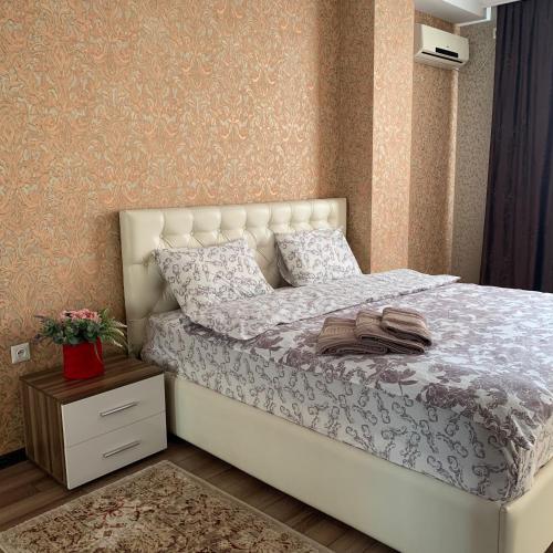 ein Schlafzimmer mit einem weißen Bett, einer Kommode und einem Nachttisch in der Unterkunft Apartment elit Bishkek in Bischkek