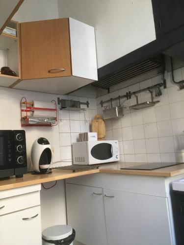 une cuisine avec des placards blancs et un comptoir avec un four micro-ondes dans l'établissement FLC, loft atypique CAMAS HYPER-CENTRE, à Marseille