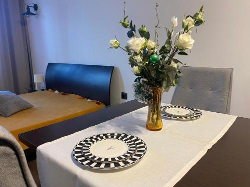 uma mesa com um vaso com rosas brancas em Studio Nr 6 em Bansko