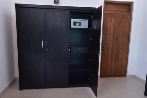 a black cabinet with a microwave in a room at MARGOSA MOUNTAIN VILLA in Galewela