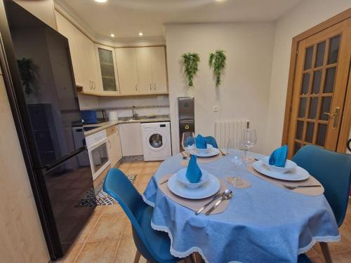 a dining room table with blue chairs and a kitchen at 614A Coqueto ático in Oviedo