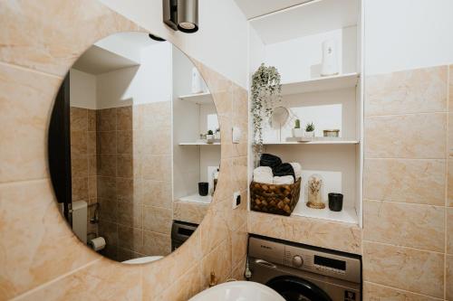 uma casa de banho com um espelho e uma máquina de lavar roupa em DOUX Apartman em Odorheiu Secuiesc