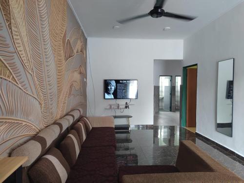ein Wohnzimmer mit einem Sofa und einem TV an der Wand in der Unterkunft JC HOMESTAY PORT DICKSON in Port Dickson