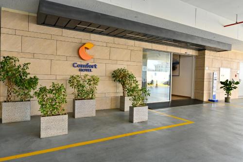 a building with potted plants in front of a building at Comfort Hotel Jeddah King Road in Jeddah
