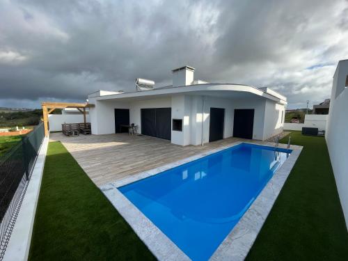 a villa with a swimming pool in front of a house at Casa Felino in Nadadouro