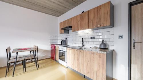 a kitchen with wooden cabinets and a table at Apart Pension Zelený grunt in Dřínov