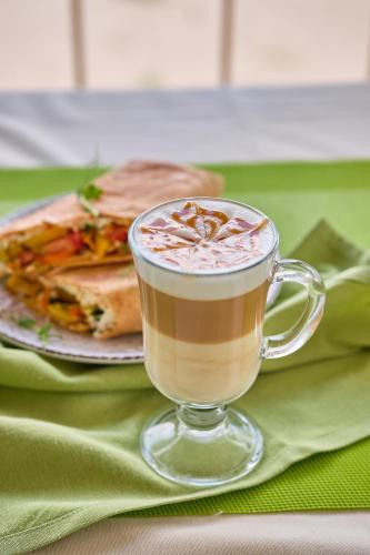 a cup of coffee on a table with a sandwich at Hotel Palma in Odesa
