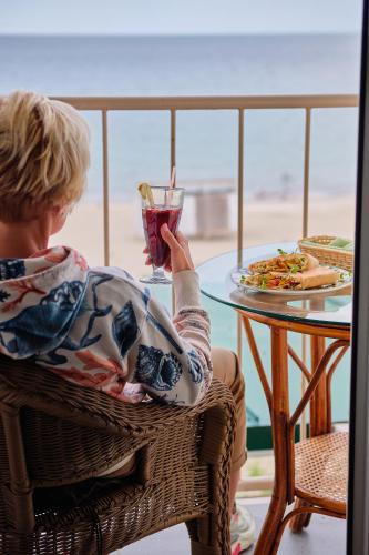 a woman sitting at a table with a drink at Hotel Palma in Odesa