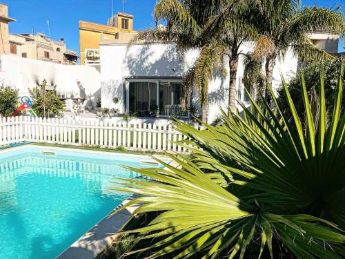 a swimming pool with a white fence and palm trees at Angolo paradiso in Castelvetrano Selinunte