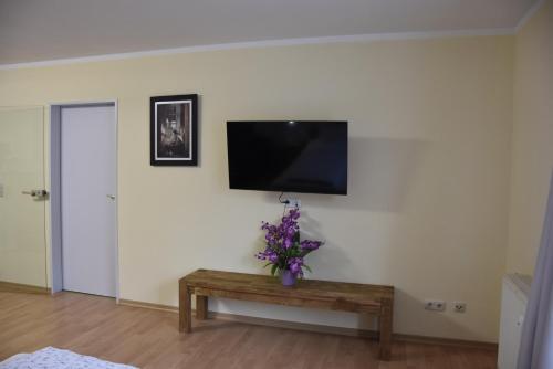 a living room with a tv and a table with flowers at Hotel Garni Am Klostermarkt in Plauen