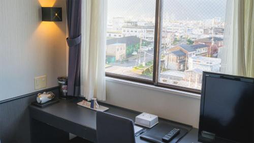 a desk with a computer and a monitor and a window at Hotel Viora in Owase