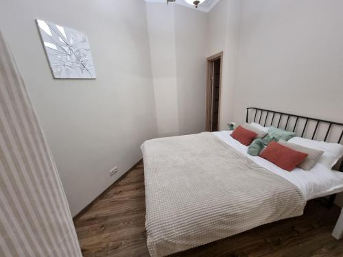 a white bedroom with a bed with red and green pillows at Art Deco One-Bedroom Suite in Library House with Free 5G WiFi in Riga