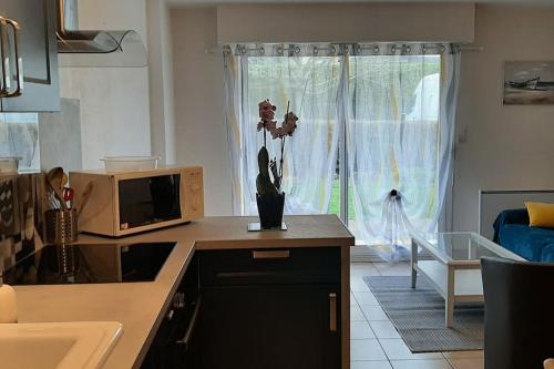 a kitchen with a vase with flowers on a counter at Hyper centre de Sarzeau, grand appartement au calme avec jardinet in Sarzeau