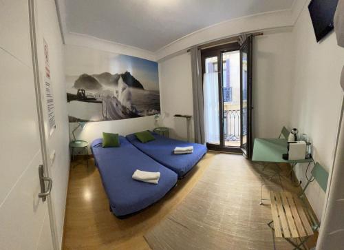 um quarto com uma cama azul e uma grande janela em Gurtxu Rooms by Sun Sebastián em San Sebastián