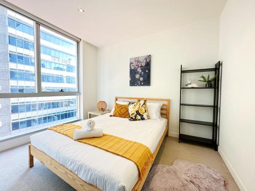 a bedroom with a large bed and a large window at Luxe Central City QV Apartment with Indoor Pool & Gym in Melbourne