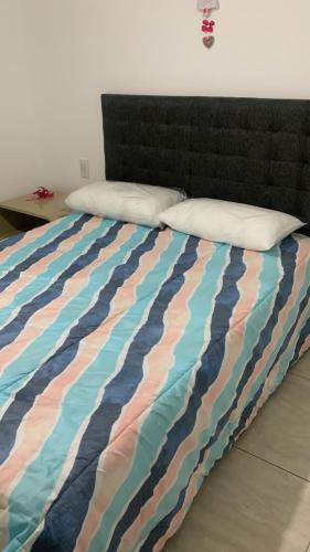 1 cama con un edredón de rayas colorido y 2 almohadas en HIPÓLITO YRIGOYEN en Villa Carlos Paz