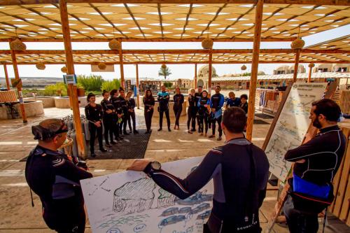 a group of people in wetsuits standing around a drawing at Marsa Shagra Village in Abu Dabab