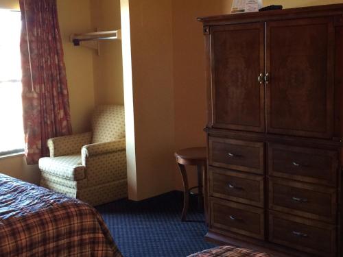 a hotel room with a dresser and a chair and a bedroom at Scottish Inn - Nashville in Nashville