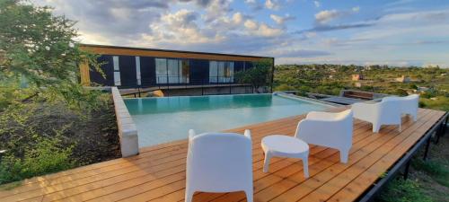 una terraza con sillas blancas y una piscina en BLACK BOX CABAÑAS A en Villa Santa Cruz del Lago