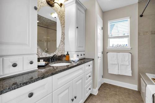a white bathroom with a sink and a mirror at Jax Beach Luxury Oasis W/ Private Pool/Jacuzzi Tub in Jacksonville Beach