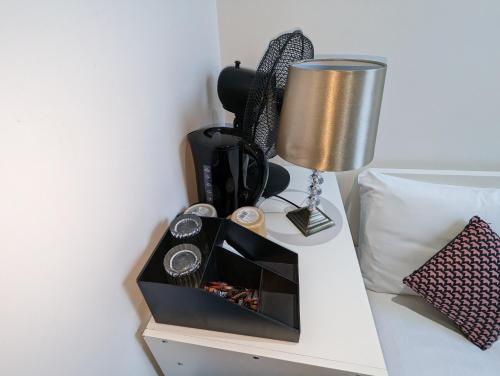 a nightstand with a clock and a lamp on a bed at Mile End- Prime location in London
