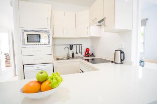 a white kitchen with a bowl of fruit on a counter at Ocean Vibes with sea view and private heated pool in Callao Salvaje