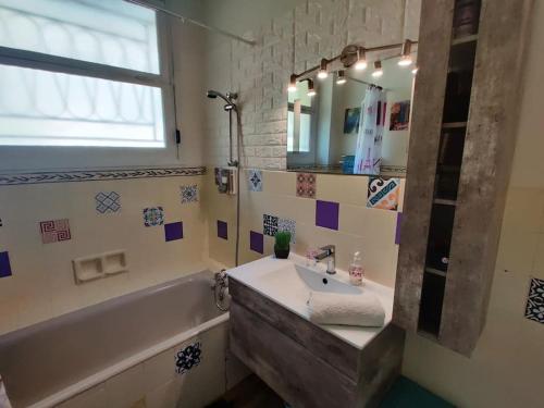 une salle de bain avec un lavabo, une baignoire et un miroir dans l'établissement Vintage flat on Villefranche bay - free car park, à Villefranche-sur-Mer