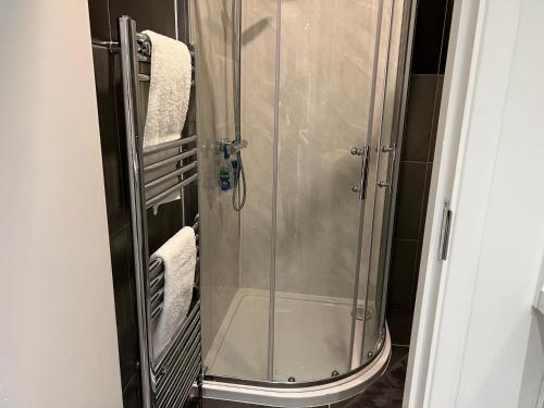 a shower with a glass door and towels in a bathroom at Luxury 1 bed apartment + 1 Sofa Bed Can sleep Up To 4 People 5 Mins Barnet Station Free Parking in Barnet