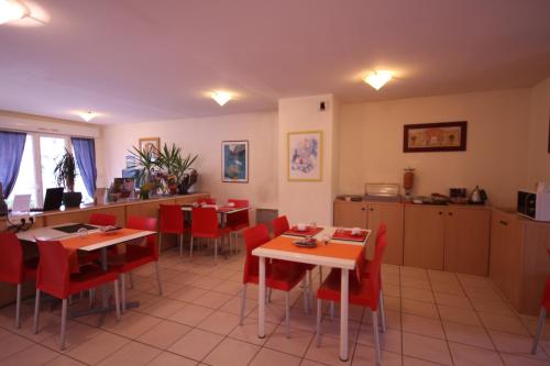 a restaurant with red chairs and tables and a kitchen at Résidence Côté Sud La Bouilladisse in La Bouilladisse