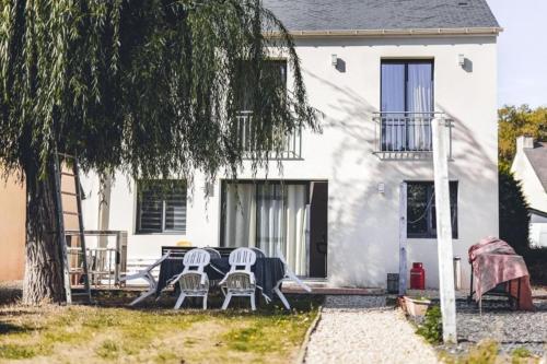 uma mesa e cadeiras em frente a uma casa branca em Villa 4ch 4Sdb à 5min de Nantes em Sainte-Luce-sur-Loire
