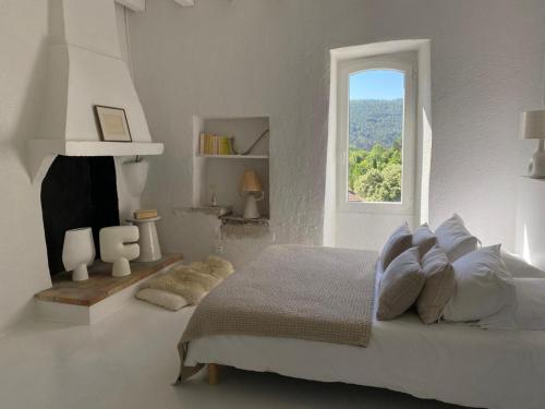 a white bedroom with a bed and a window at Magnifique Mas Cevenol in Anduze