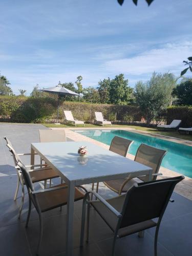 - une table et des chaises à côté de la piscine dans l'établissement Villa Sara avec sa piscine et jardin, à Marrakech