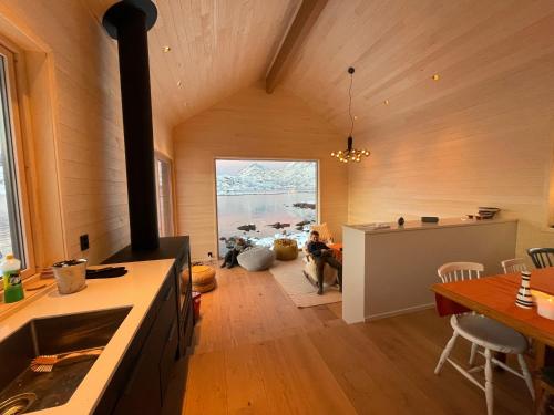 a kitchen with a stove and a dining room with a table at Superior Cabin with Private Beach Lofoten 