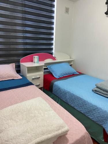 una camera con due letti e una scrivania di Central departamento en recinto privado Aire acondicionado Wifi Estacionamiento a Rancagua