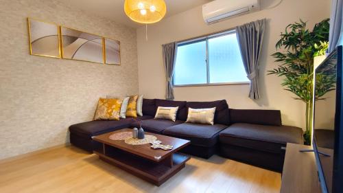 a living room with a couch and a table at Tsukiyume Kan - 10m to USJ, Tennoji & KIX Direct, 無料ガレージ付, 和モダン貸切一軒家, ユニバーサルスタジオジャパン近隣 in Osaka