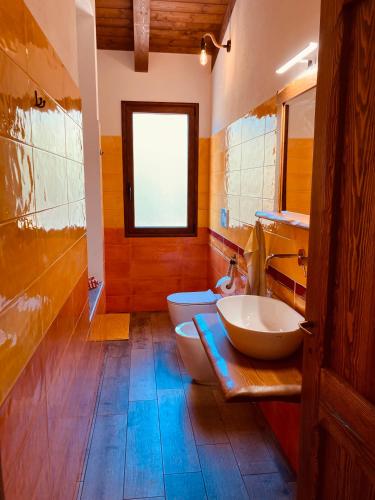 a bathroom with two sinks and a toilet and a window at Coru & Bentu in Fluminimaggiore