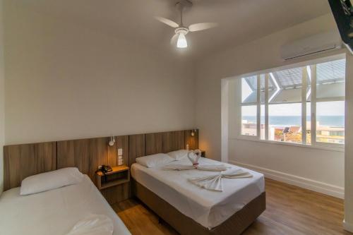 a bedroom with two beds and a large window at Farol Hotel in Torres
