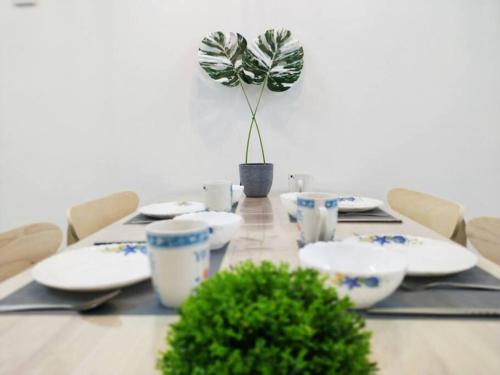 a table with plates and a potted plant on it at 575 Port Dickson # U Homestay - 2KM to Beach & Free Wifi in Port Dickson