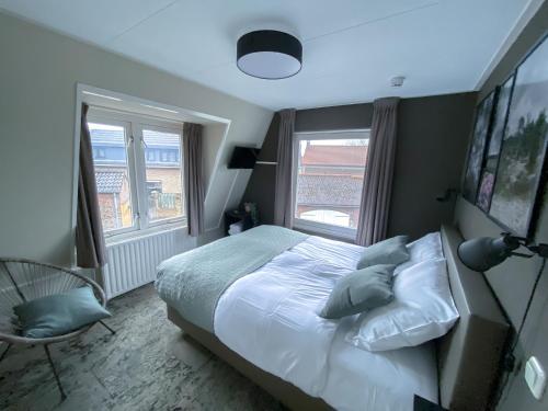 a bedroom with a bed and two windows at Hotel de Slapende Hollander in Kaatsheuvel
