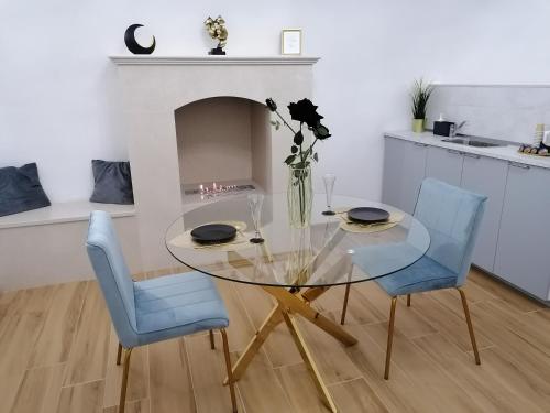 a dining room with a glass table and two blue chairs at Appartamenti Mascagni in Sannicandro di Bari