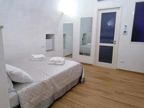 a white bedroom with a bed with towels on it at Appartamenti Mascagni in Sannicandro di Bari