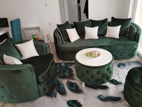 a living room with a green couch and two chairs and a table at Stari Hrast 2 in Prolomska Banja
