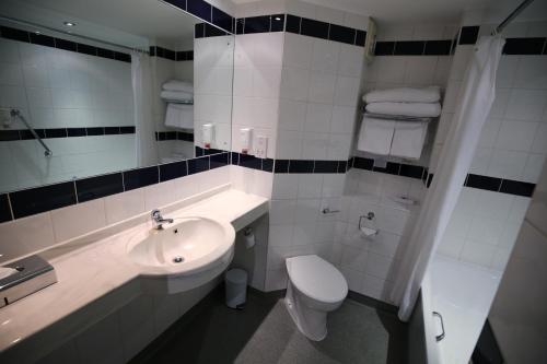 a white bathroom with a sink and a toilet at Ramada Oxford in Waterstock