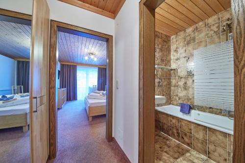 a bathroom with a tub and a sink and a bath tub at Hotel Gamshag in Saalbach Hinterglemm