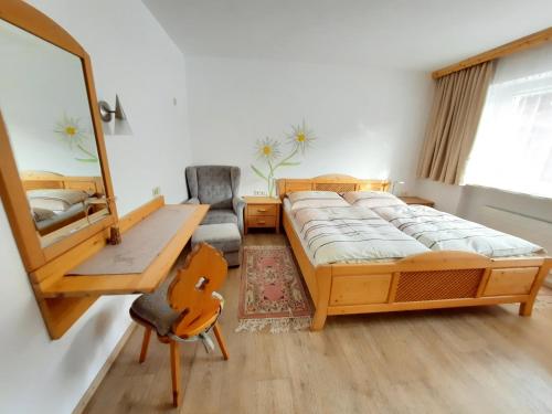 a bedroom with two beds and a mirror and a chair at Appartement Schilcher in Oberau