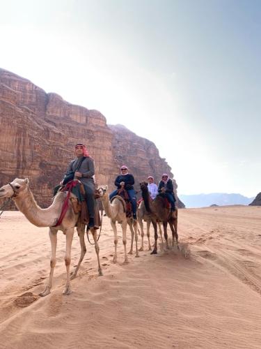 a group of people riding camels in the desert at Rum desert magic in Wadi Rum